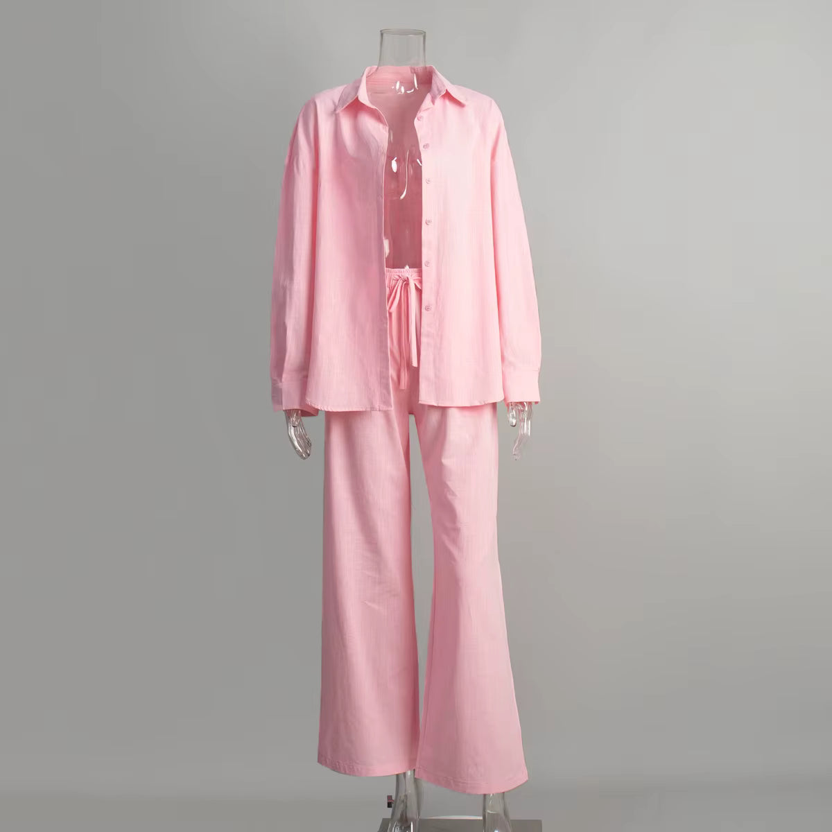 Pink long-sleeve button-up shirt and matching drawstring trousers on a clear mannequin.